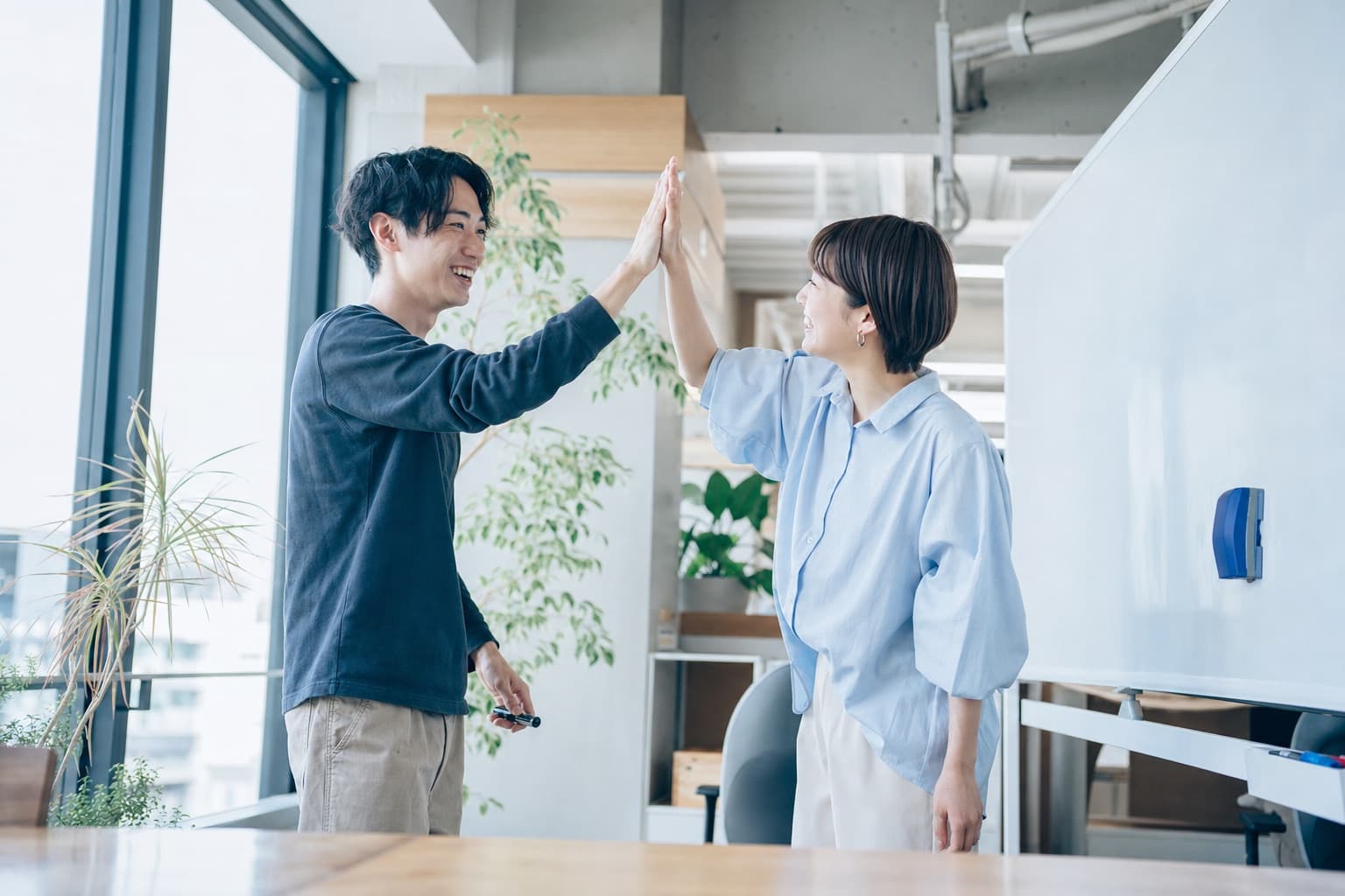 明るいオフィスでハイタッチしている様子